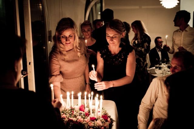 Friends lighting candles on a birthday cake